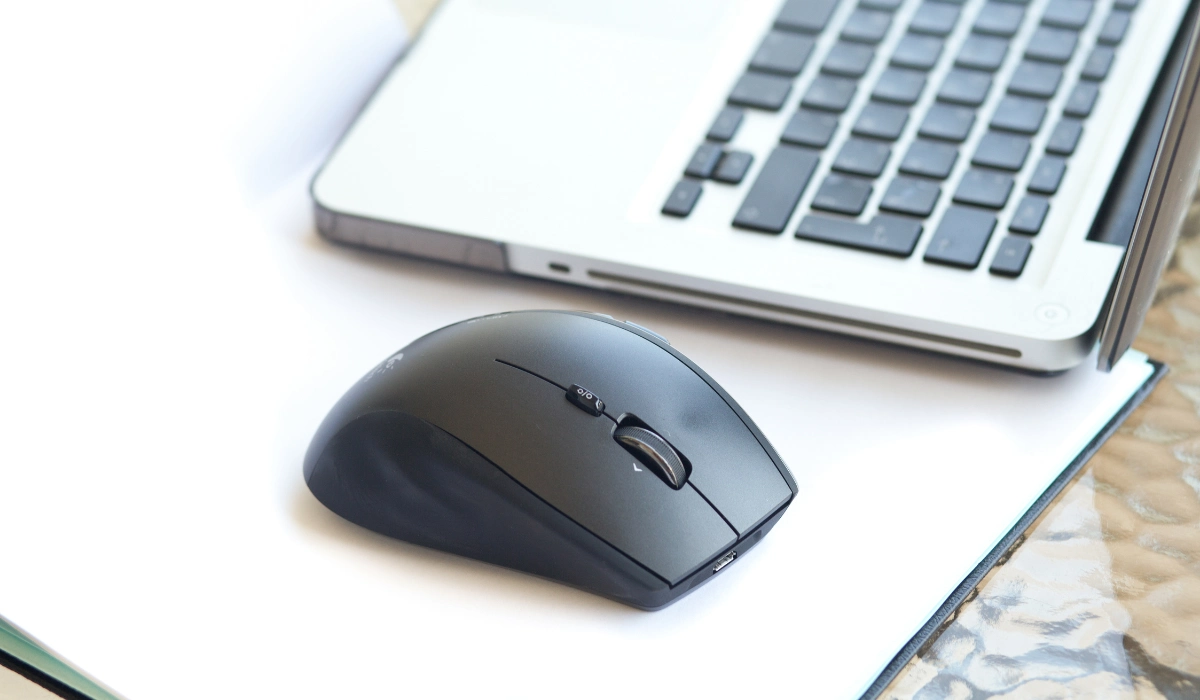 Una persona conectando el receptor USB de un ratón inalámbrico a un puerto de su portátil